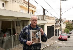 O jornalista Jorge Tadeu da Silva, um dos afetados pelo acidente com o avião modelo Fokker 100 da TAM que vitmou 99 pessoas em 1996, segura foto de como ficou a casa dele na rua Luís Orsini de Castro, no Jabaquara. - Foto: Rovena Rosa/Agência Brasil